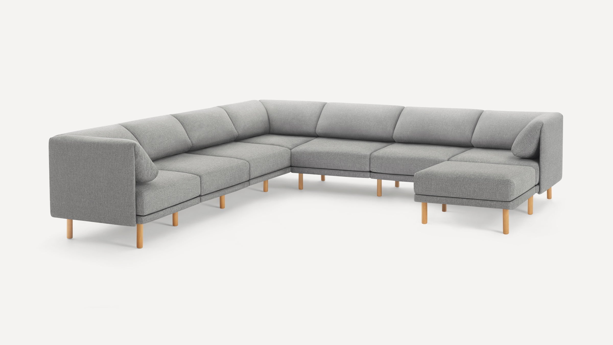 Modern L-shaped sectional sofa in light gray fabric with wooden legs and cushioned backrests, minimalist design.