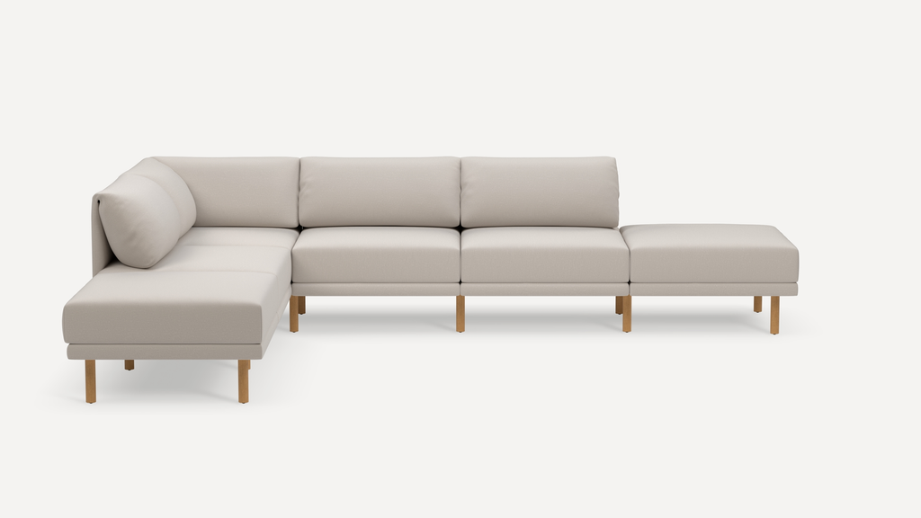 Modern L-shaped beige sectional sofa with wooden legs, featuring six seat cushions and three back cushions, minimalistic design.