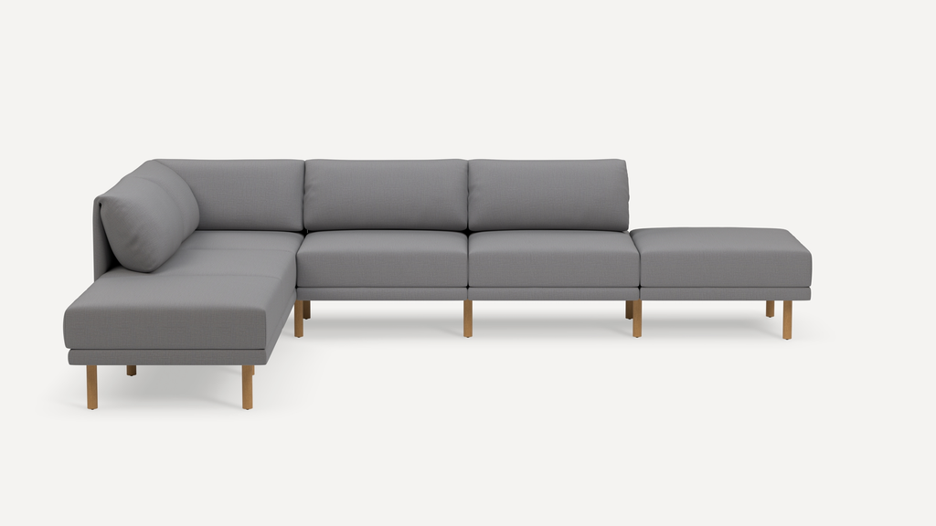 Modern L-shaped sectional sofa with light gray fabric upholstery and light wooden legs on a white background.