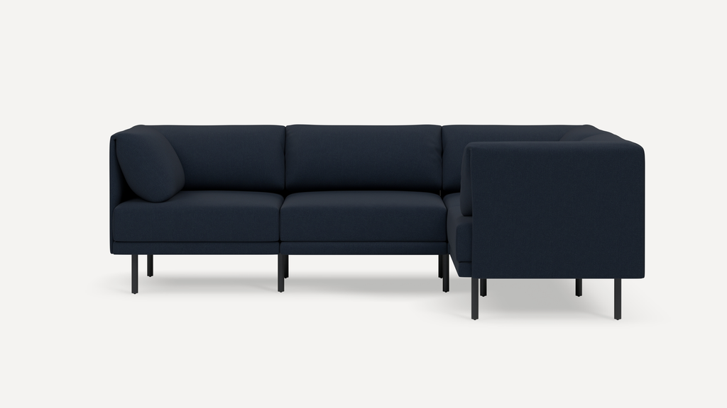 Modern navy blue L-shaped sectional sofa with thin black metal legs and plush cushions on plain white background.