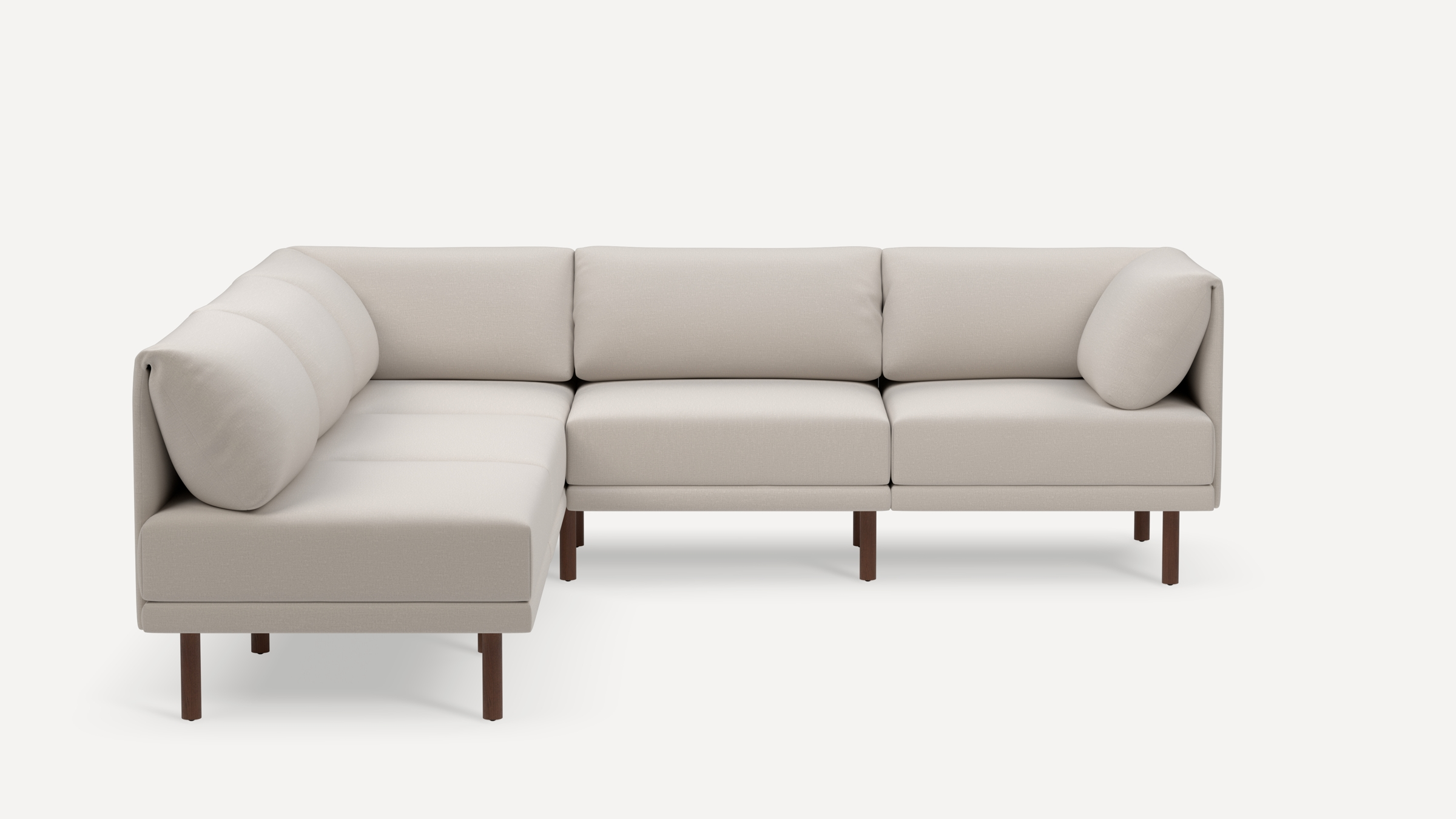Modern L-shaped sectional sofa with beige fabric upholstery, cushioned backrest, and dark wooden legs on a white background.