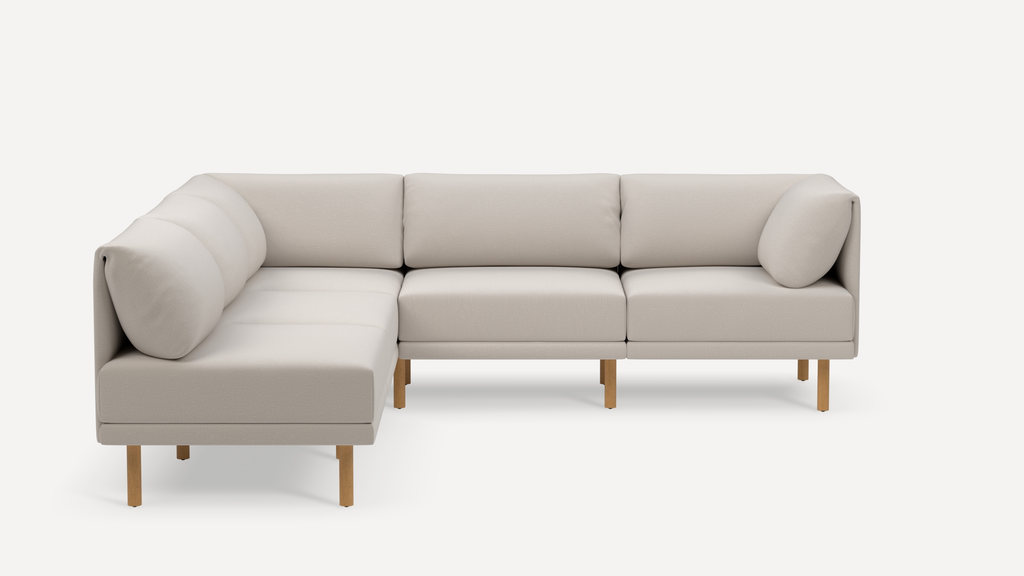Modern L-shaped beige fabric sectional sofa with wooden legs, plush cushions, and clean minimalist design on white background.