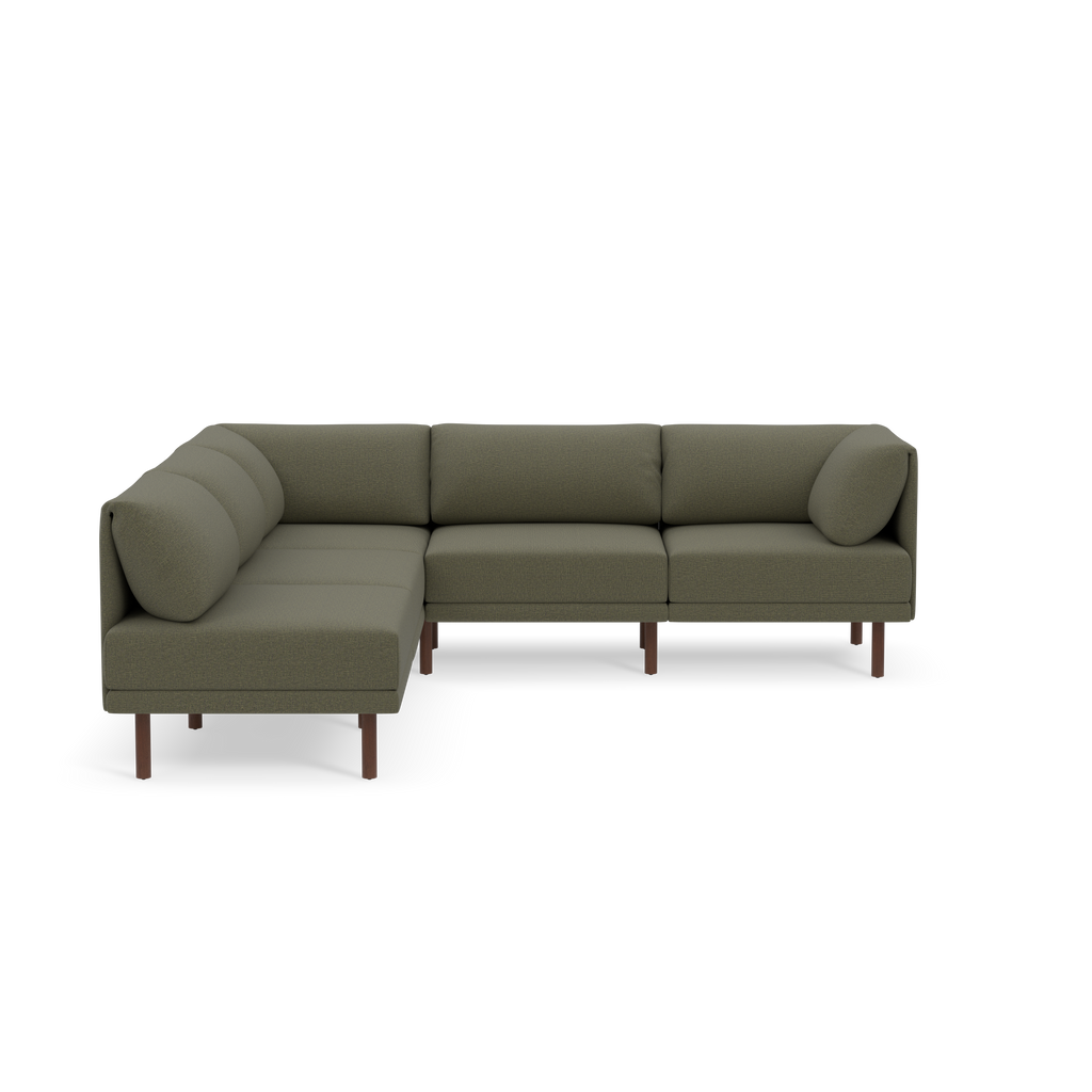 Green L-shaped modern sectional sofa with rounded cushions and wooden legs on a black background.