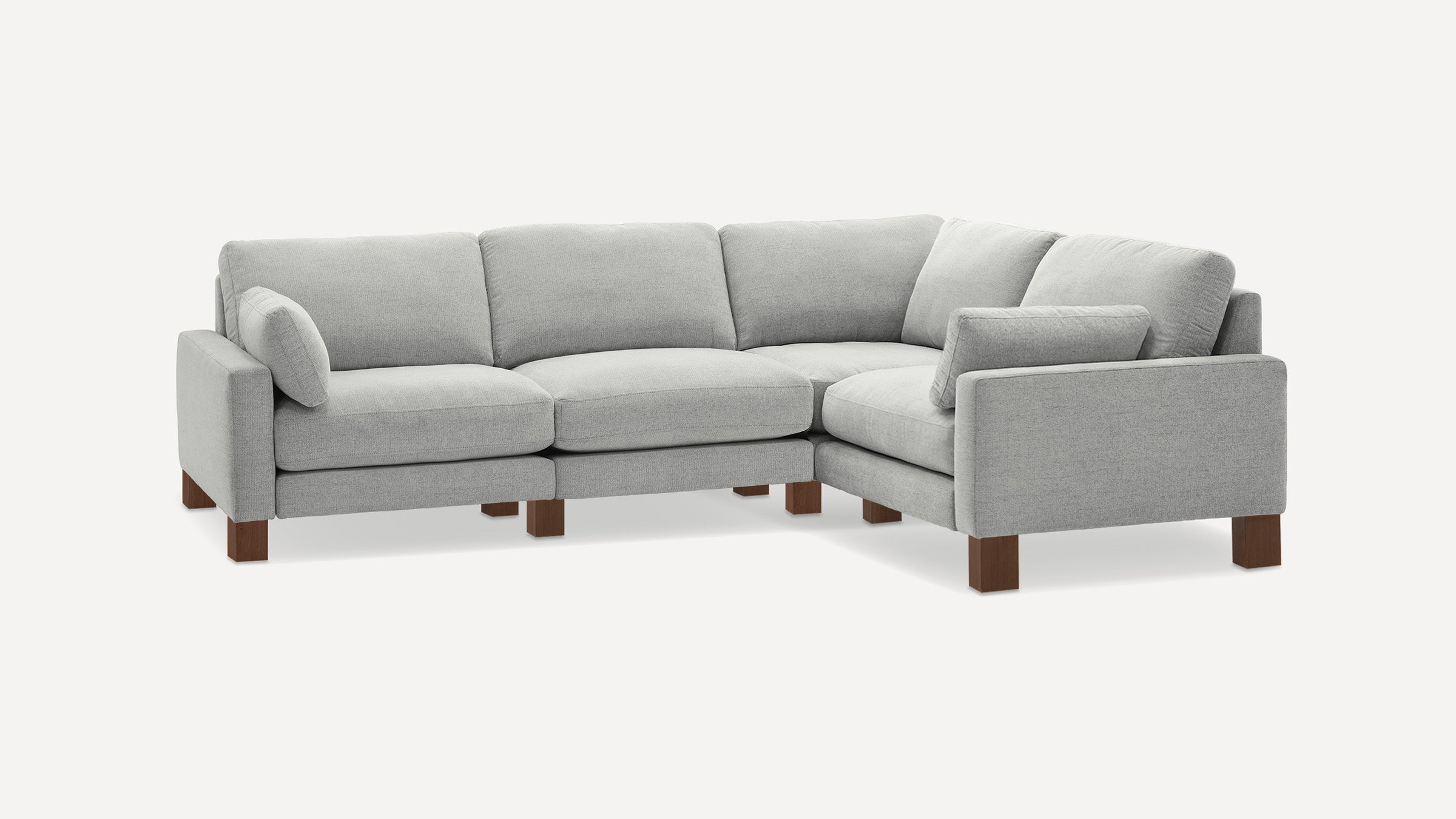 Light gray upholstered L-shaped sectional sofa with wooden block legs and multiple cushions.
