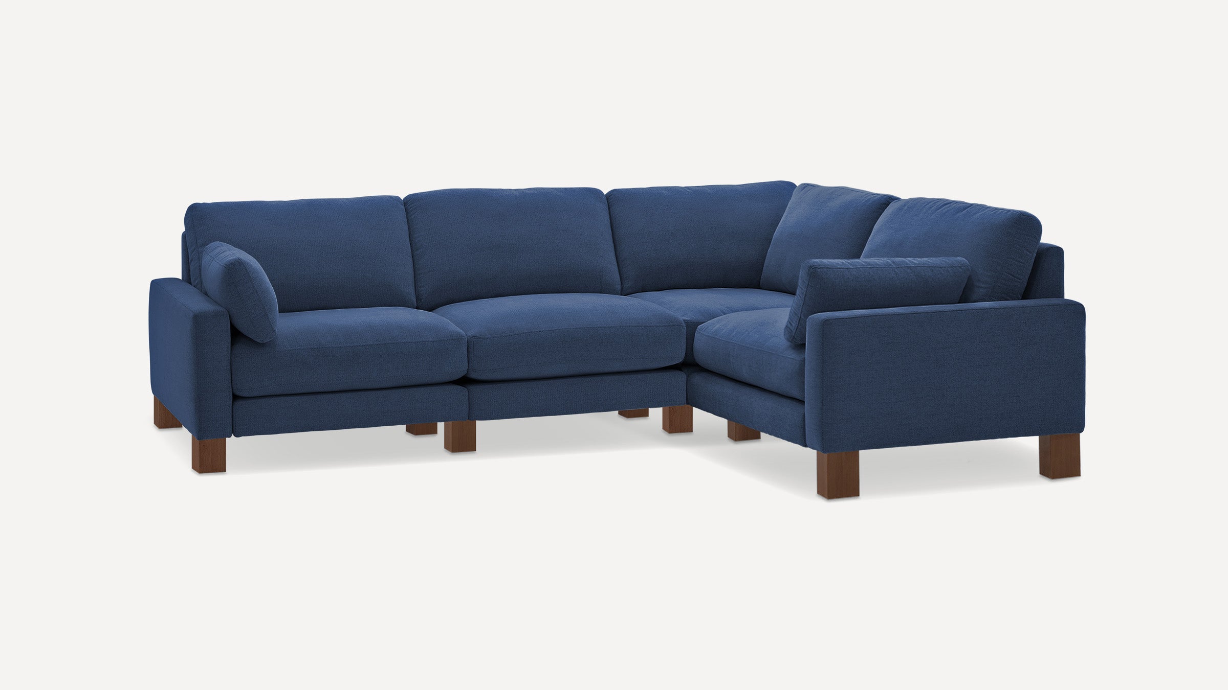 Blue fabric sectional sofa with wooden legs, cushioned seats, and backrests, styled with matching throw pillows.