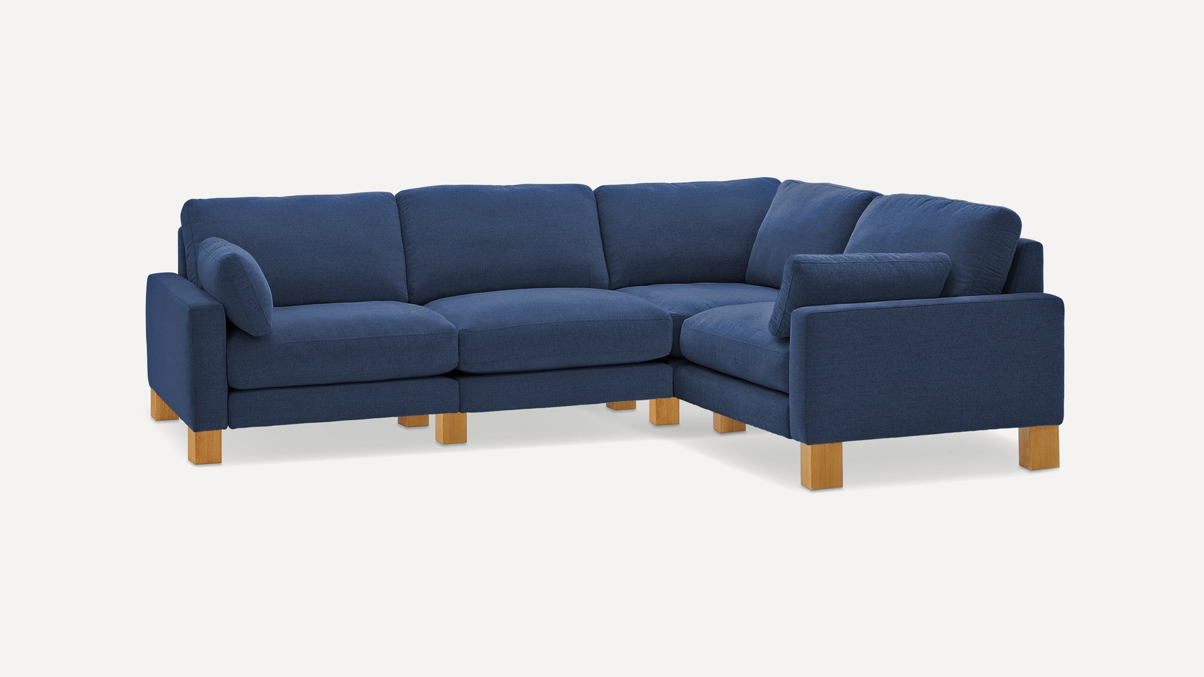 L-shaped sectional sofa with deep blue fabric upholstery and light wooden legs, featuring plush back and side cushions.