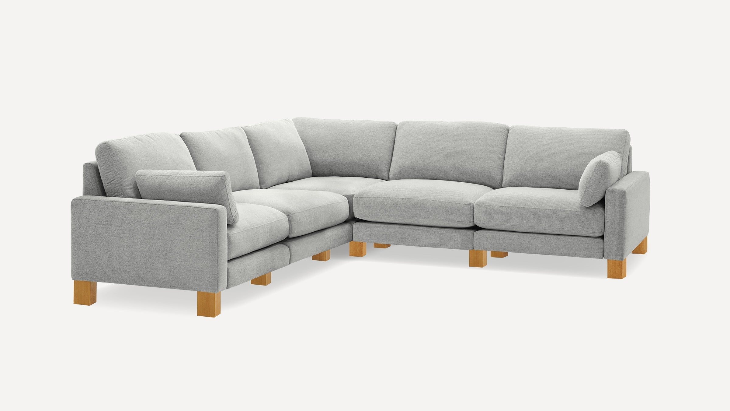 Light gray fabric L-shaped sectional sofa with wooden legs and two matching side cushions on each armrest.