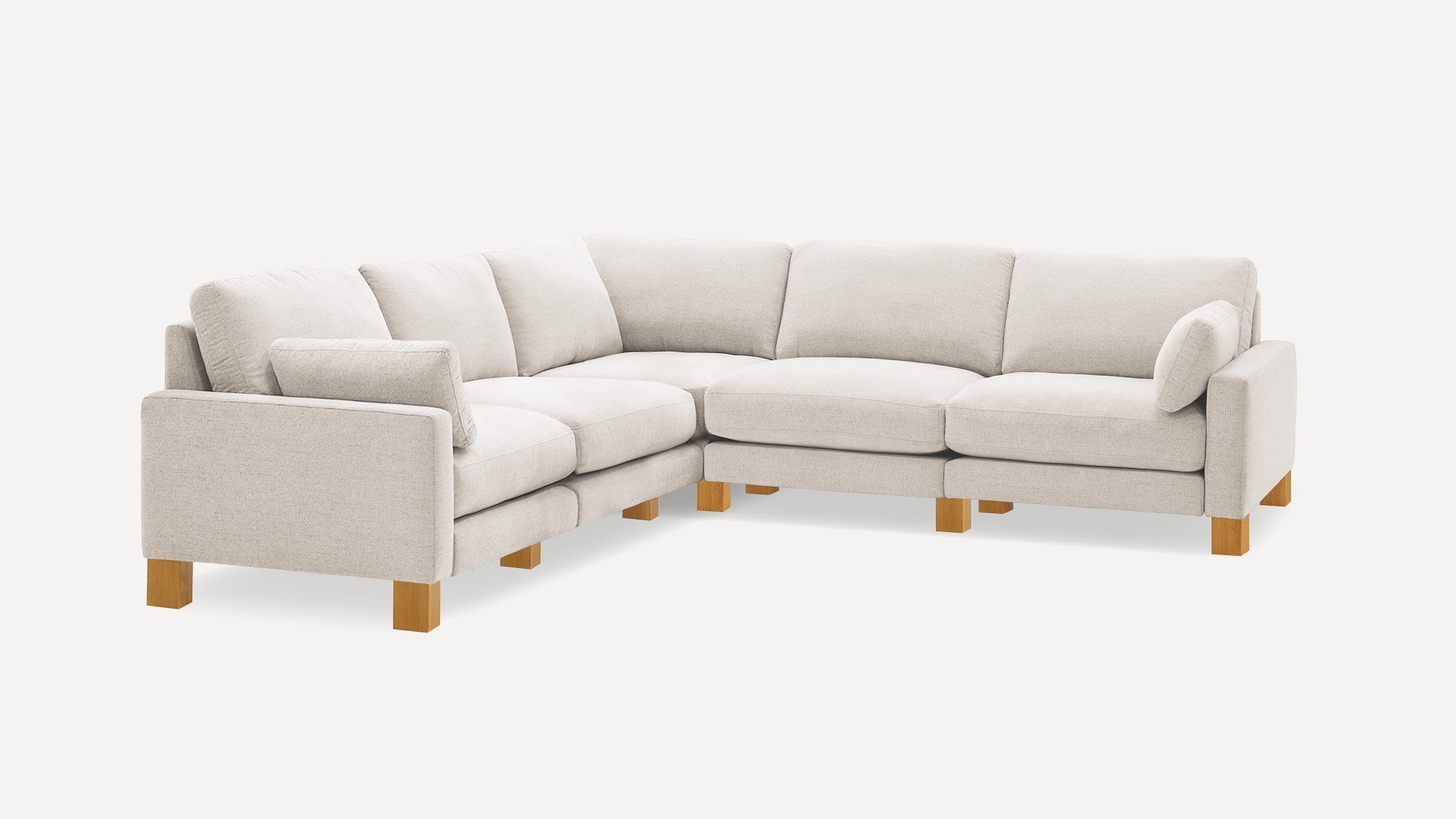 Light beige L-shaped sectional sofa with wooden legs and multiple cushions, offering a modern and cozy seating arrangement.