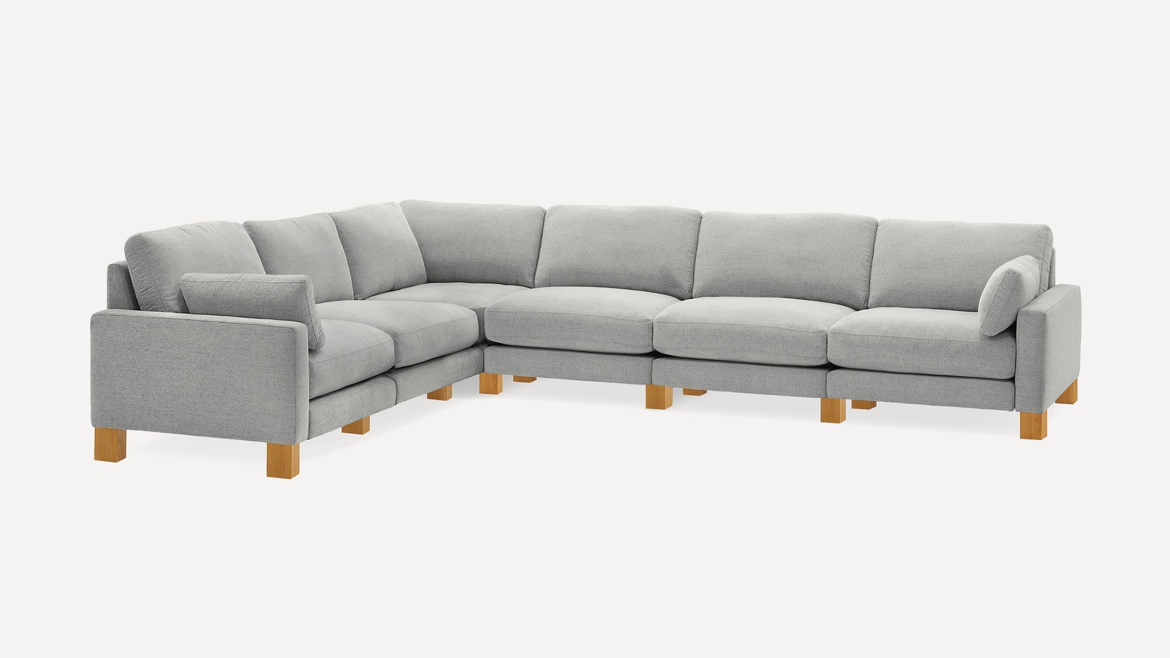 Large light grey L-shaped sectional sofa with wooden legs and cushioned armrests on a white background.