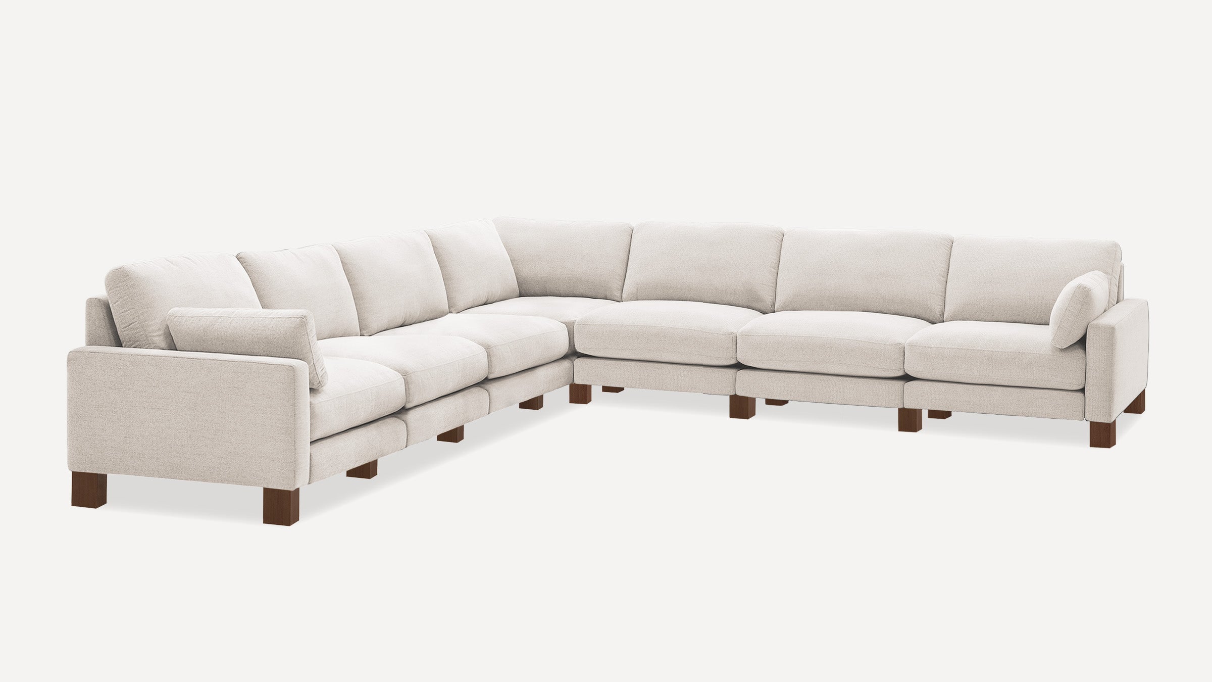 Large L-shaped sectional sofa in light beige fabric with clean lines, supportive cushions, and wooden block legs.