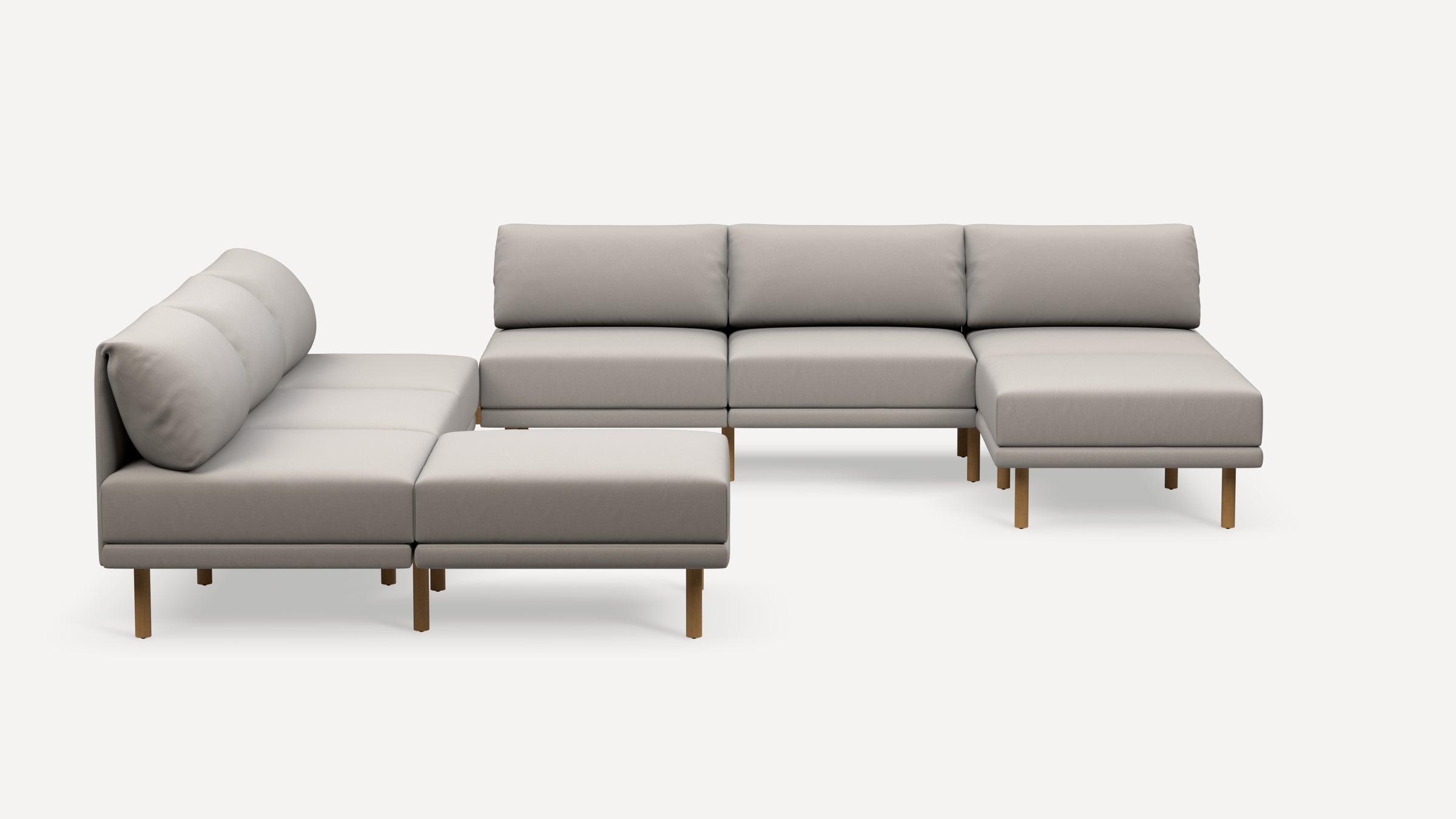 Modern L-shaped sectional sofa in light gray fabric with wooden legs, featuring low back cushions and a minimalist design.