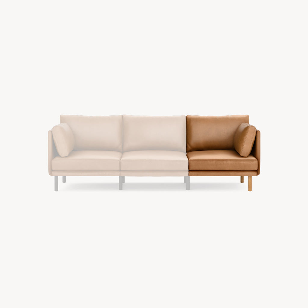 Modern sectional sofa with a beige fabric and brown leather L-shaped corner, featuring wooden legs and plush cushions.