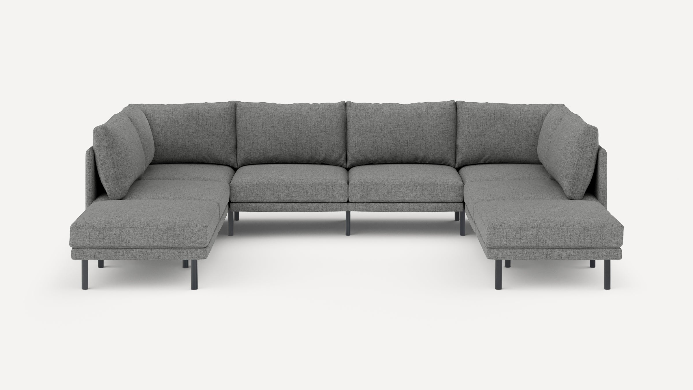 Large U-shaped sectional sofa in grey fabric with cushioned seats and backs, supported by slim black legs.