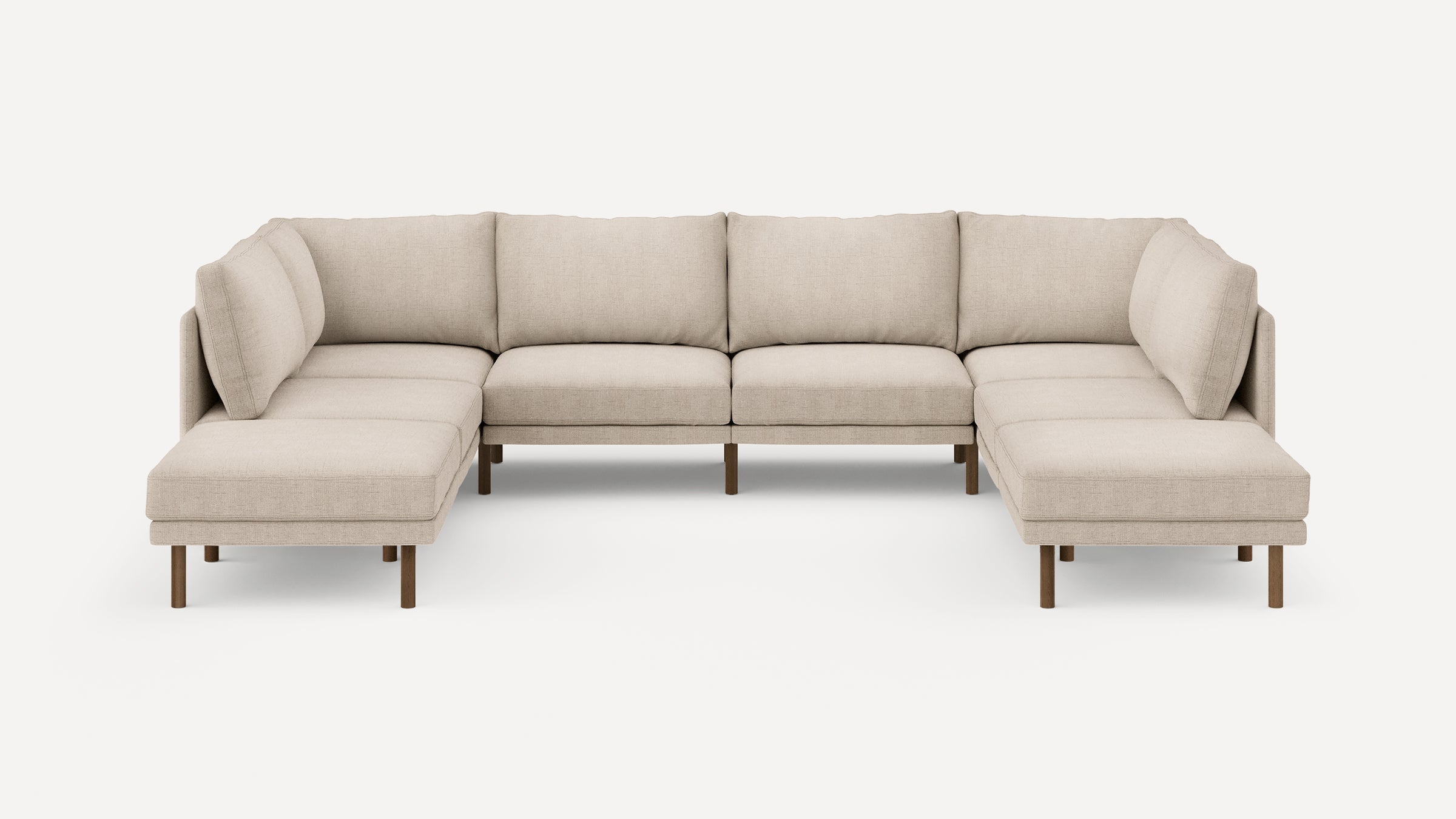 Beige upholstered U-shaped sectional sofa with wooden legs, featuring clean lines and plush back cushions.