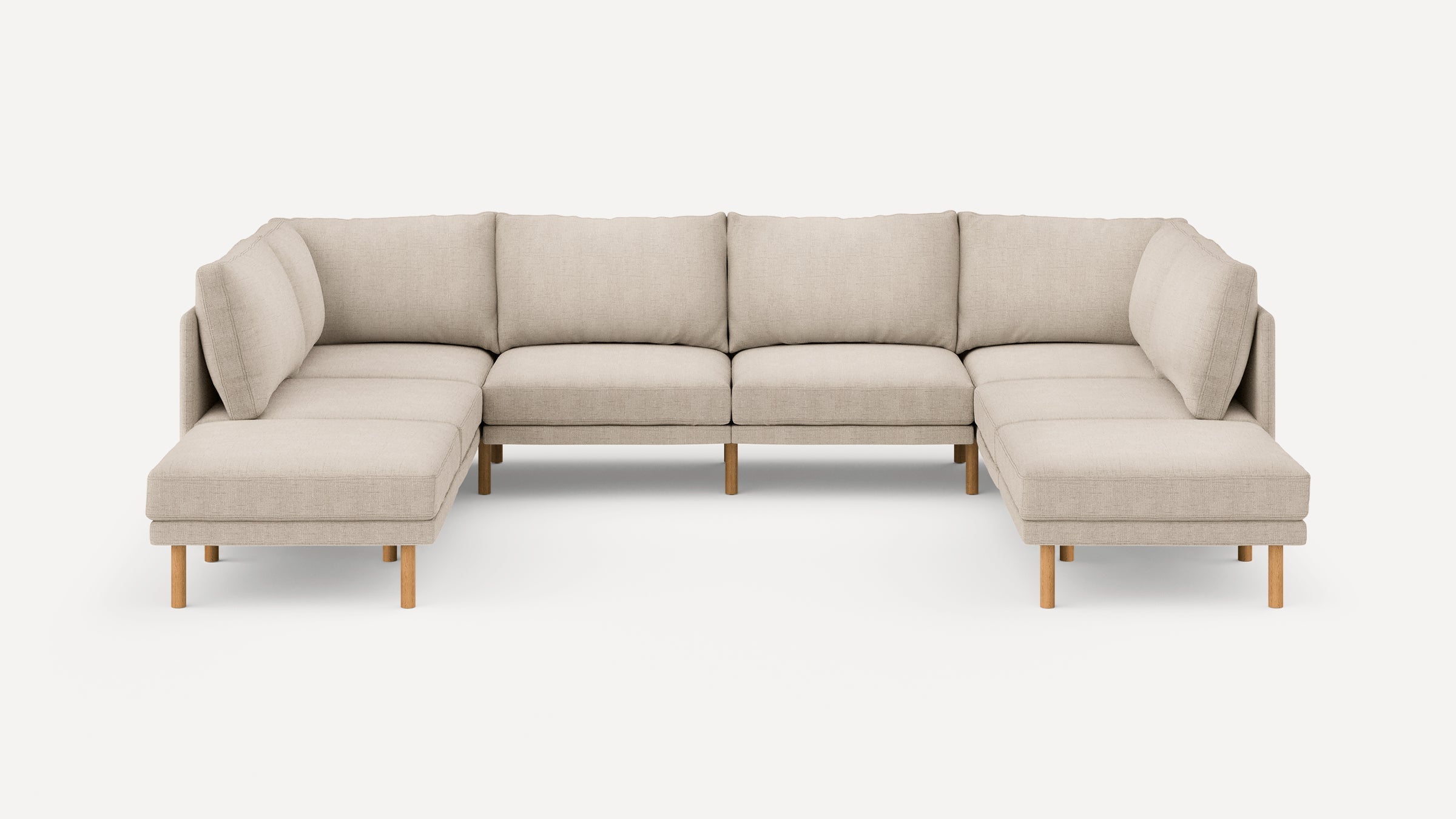 Large beige fabric sectional sofa with wooden legs, featuring cushioned seats and backrests in a U-shaped design.