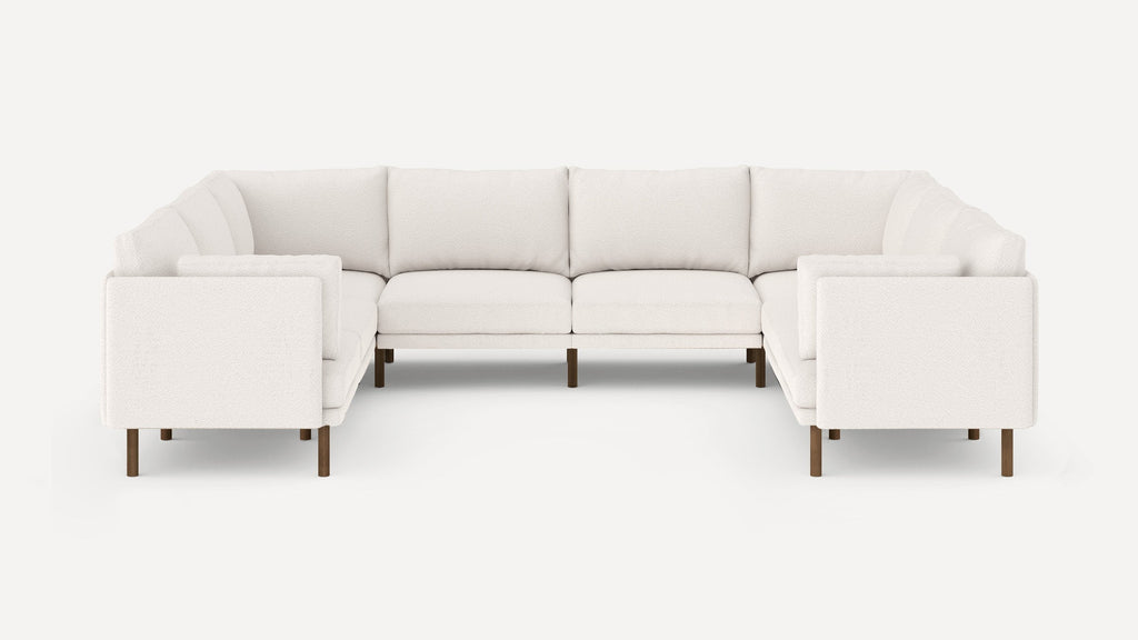 White L-shaped sectional sofa with plush cushions and dark wooden legs, set against a plain light background.