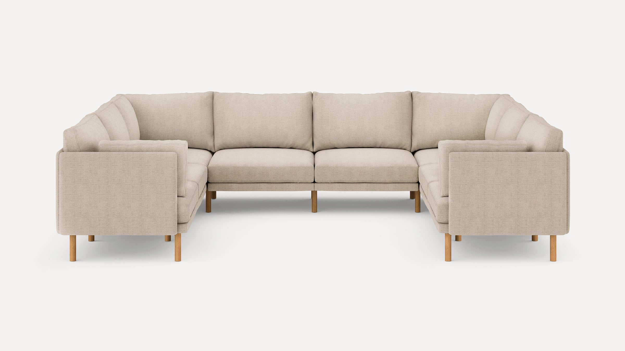 Beige L-shaped sectional sofa with wooden legs, plush cushions, and clean, modern design against a white background.