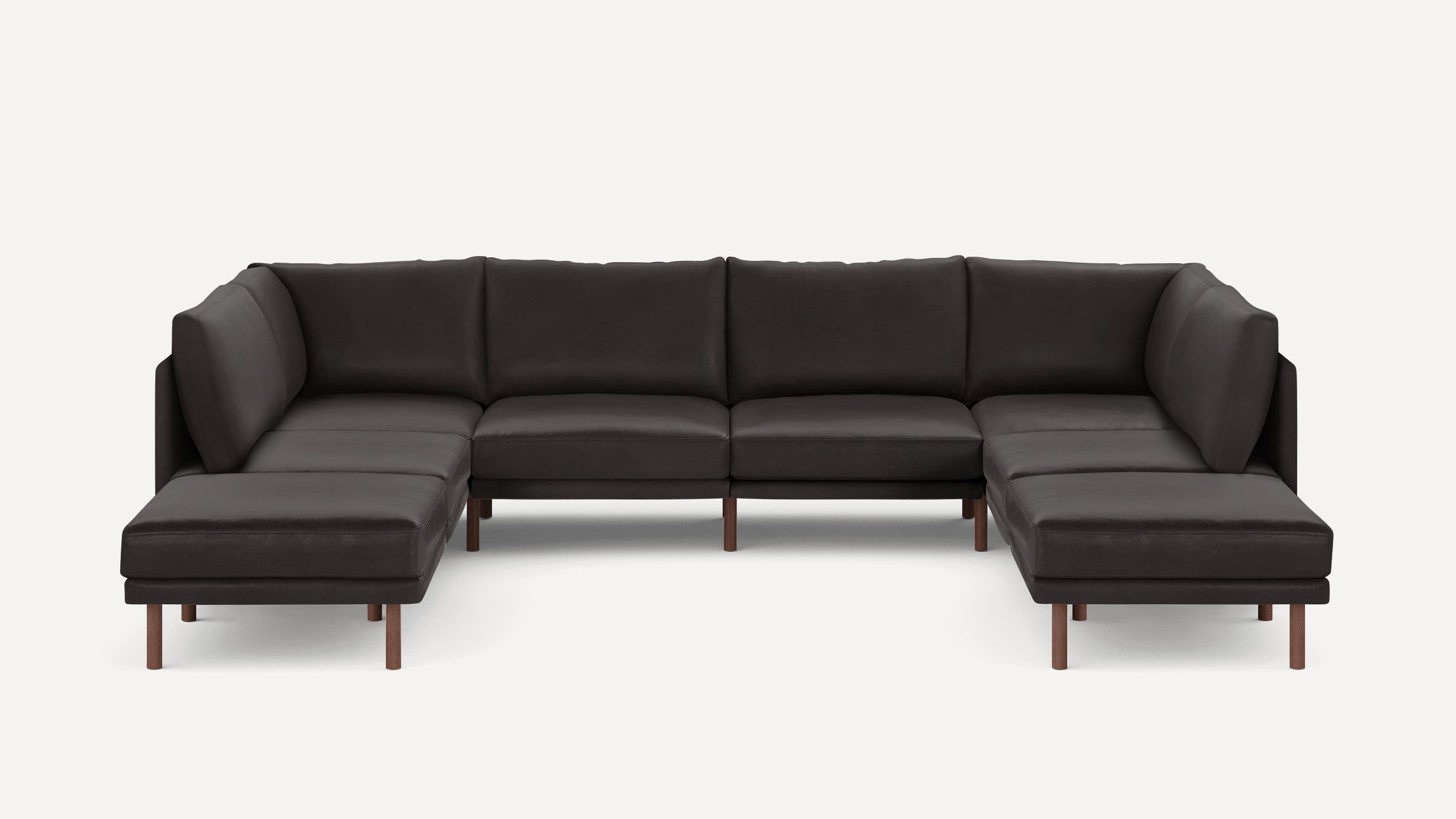 Large modern U-shaped sectional sofa in dark gray leather with minimalist wooden legs on white background.