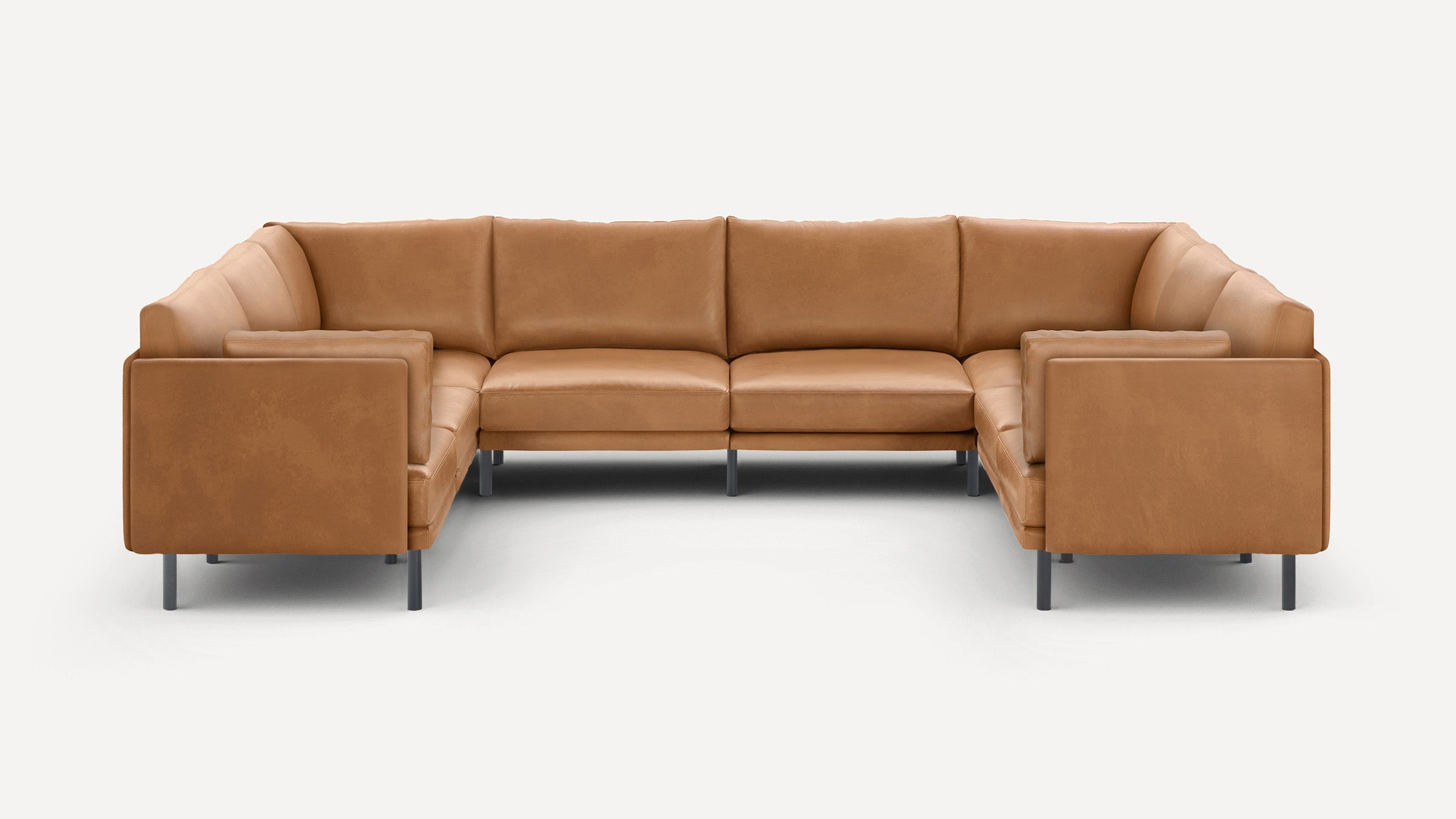 Large U-shaped sectional sofa in light brown leather with slim black metal legs, plush cushions, and clean modern design.