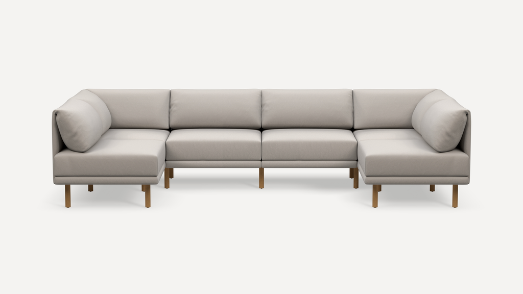 Modern beige fabric sectional sofa with wooden legs, featuring L-shaped design and cushioned backrests on both ends.
