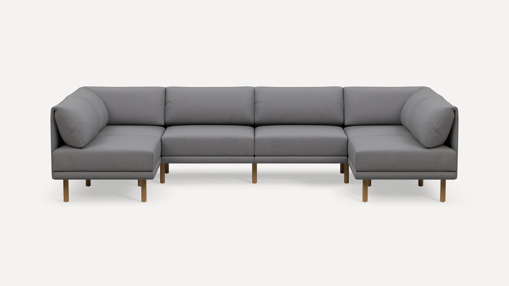 Modern gray fabric U-shaped sectional sofa with wooden legs and padded cushions, set against a plain white background.