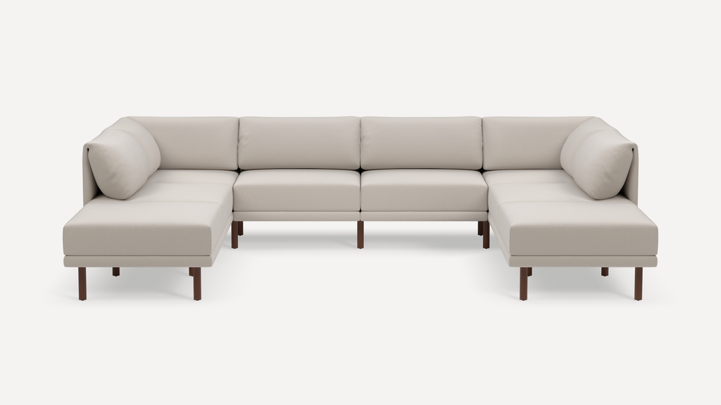 Modern U-shaped sectional sofa with light beige fabric upholstery, cushioned backrests, arms, and wooden legs, designed for spacious seating.