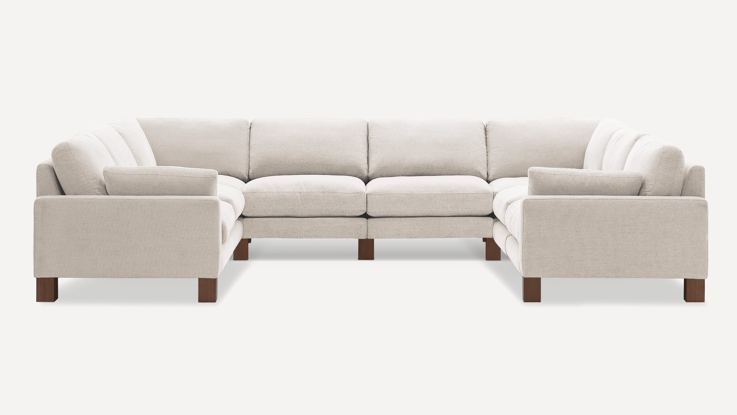 Large U-shaped sectional sofa with beige fabric upholstery and wooden legs, featuring plush cushions and straight armrests.