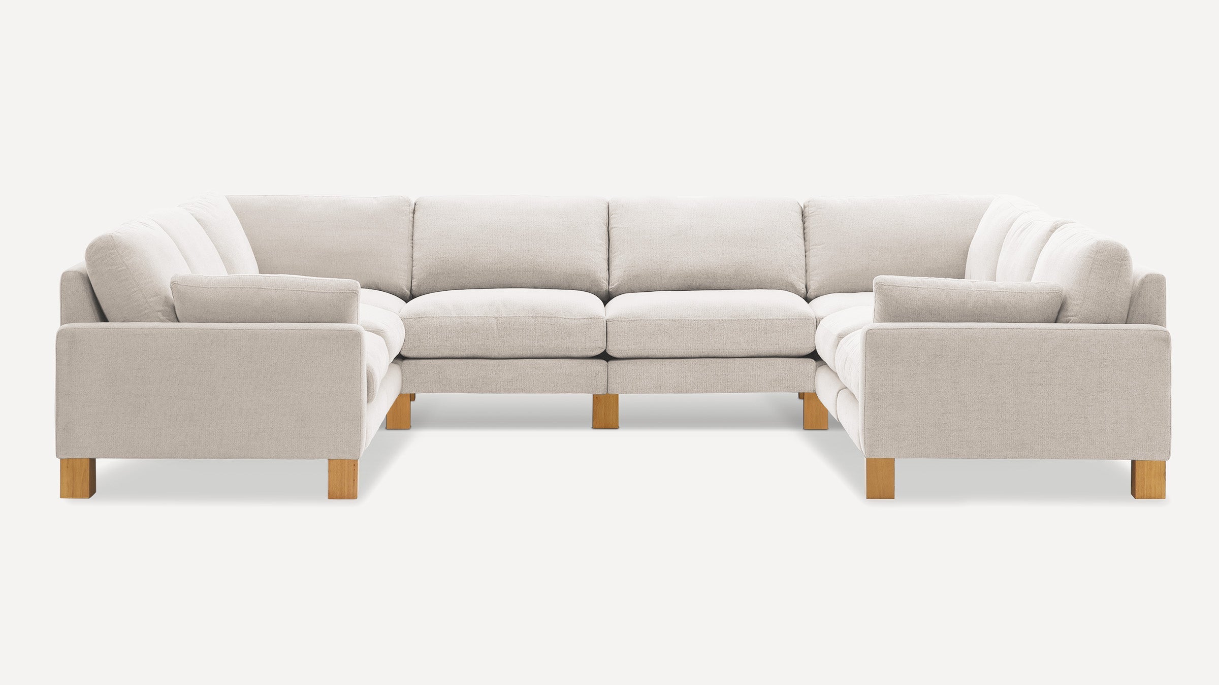 Large U-shaped sectional sofa with light beige fabric upholstery and exposed wooden legs against a white background.