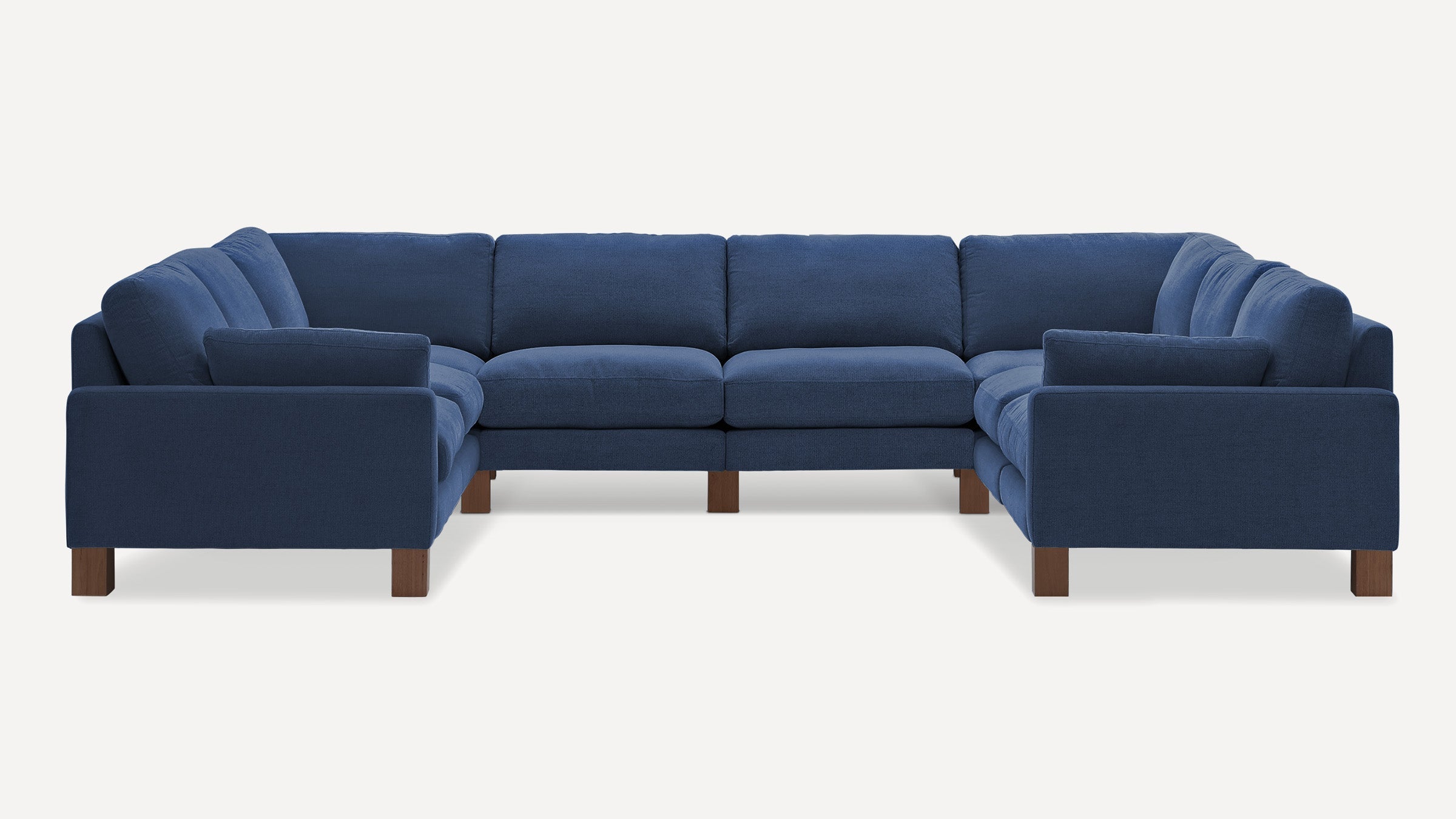 Large U-shaped sectional sofa upholstered in deep blue fabric with wooden block legs and plush cushions.
