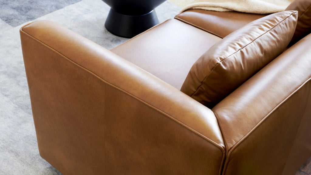 brown leather sofa with pillows and a throw pillow on the back of the couch