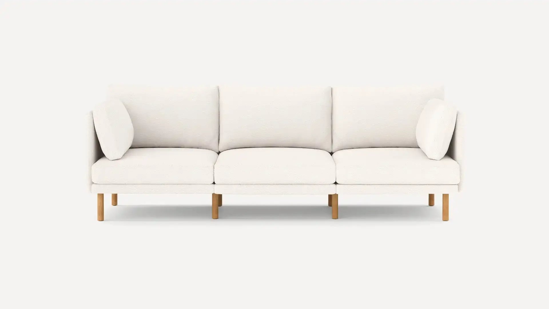 Modern three-seater sofa with white upholstery, clean lines, wooden legs, and matching cushions on each side.
