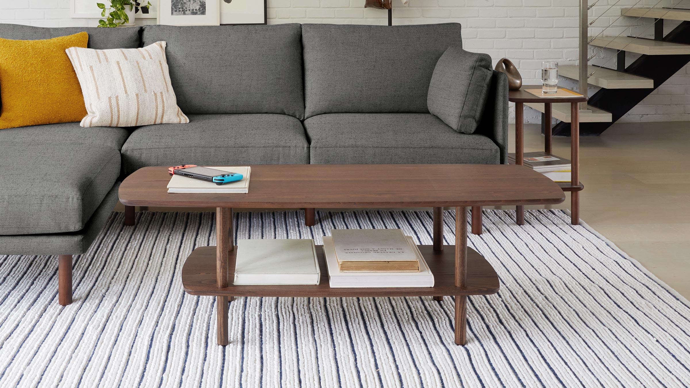 a modern living room with a gray sectional sofa, wooden coffee table, and striped rug