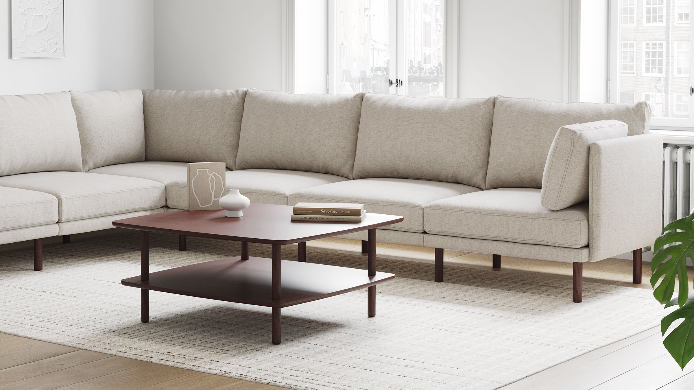 a beige sectional sofa with wooden legs and a wooden coffee table on the side of the sofa