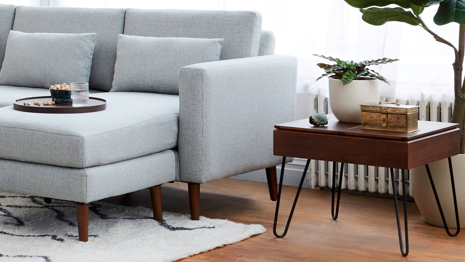 modern light gray sectional sofa with wooden legs and a round coffee table on a white rug
