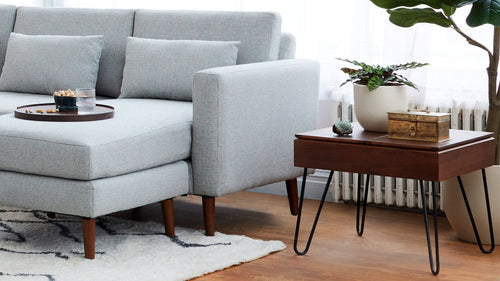 modern light gray sectional sofa with wooden legs and a round coffee table on a white rug