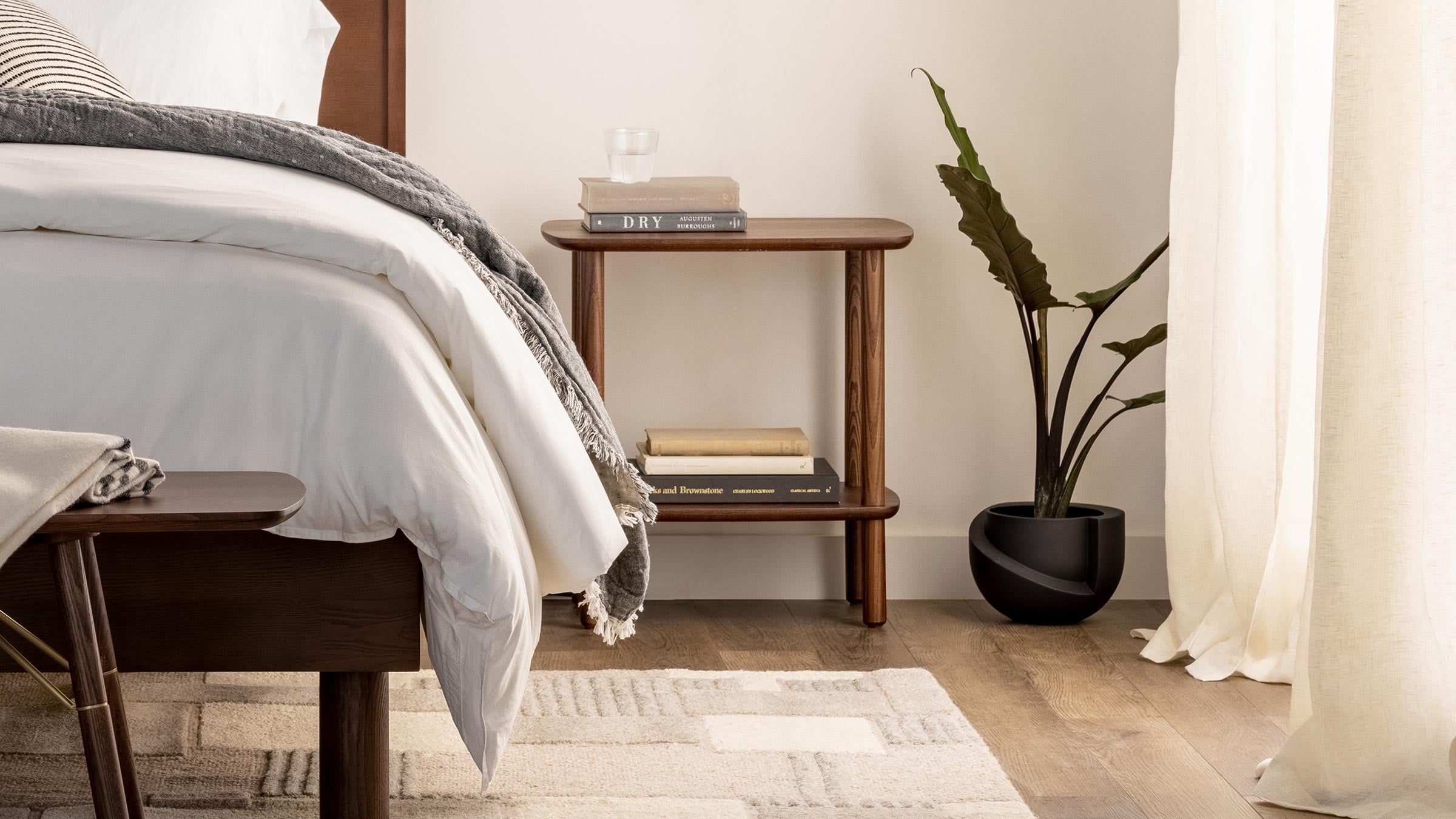 a bedroom with a bed, nightstand, and plant