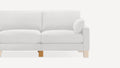 Partial view of a light gray fabric sofa with wooden legs and a matching round cushion on the right armrest.
