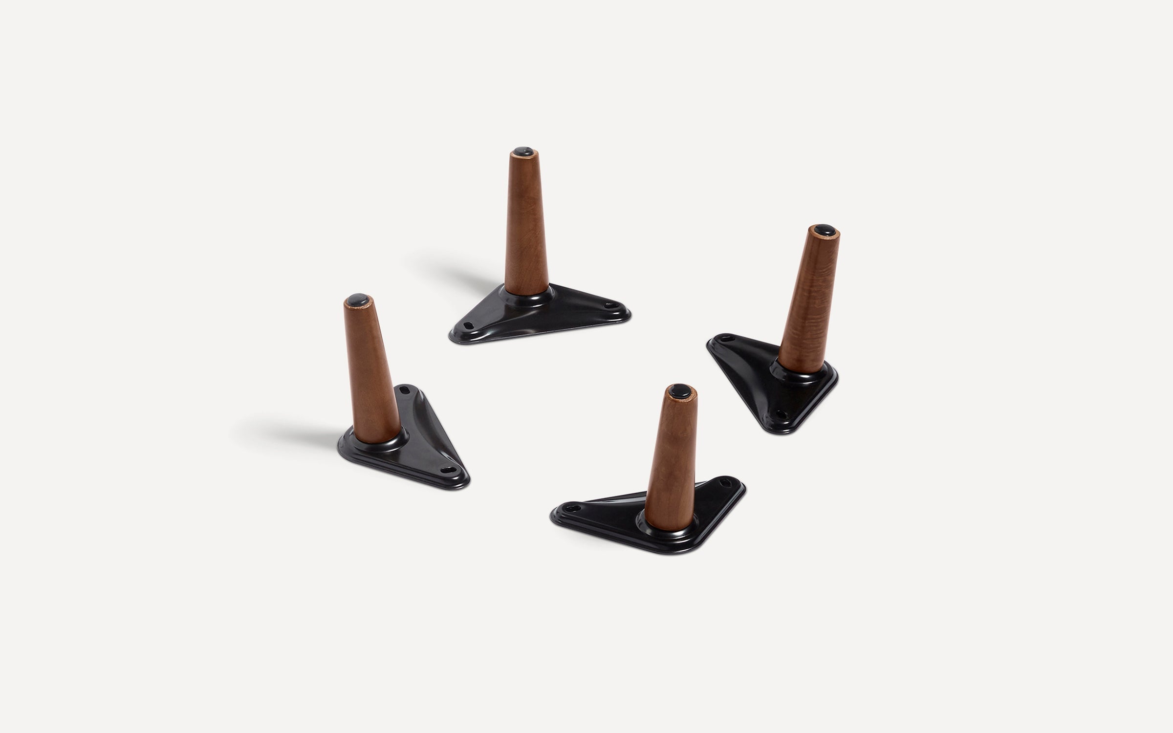 Four tapered wooden furniture legs with black triangular metal mounting plates on a white background.