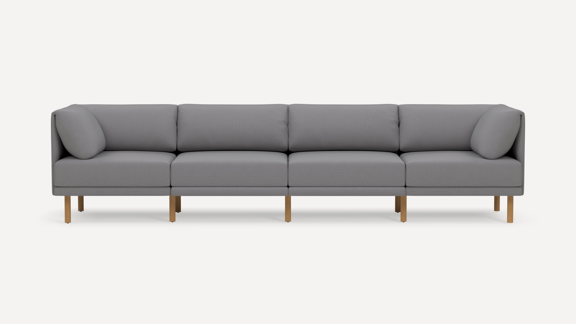 Modern light gray sectional sofa with wooden legs, featuring four seat cushions and two angled cushions on each end.
