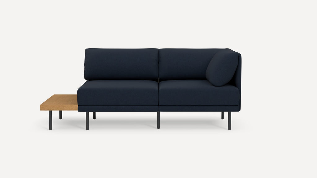 Modern navy blue sectional sofa with attached wooden side table and slim black metal legs, minimalist design.