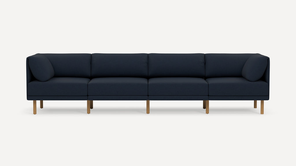 Modern navy blue four-seater sofa with plush cushions and light wooden legs, displayed against a plain white background.