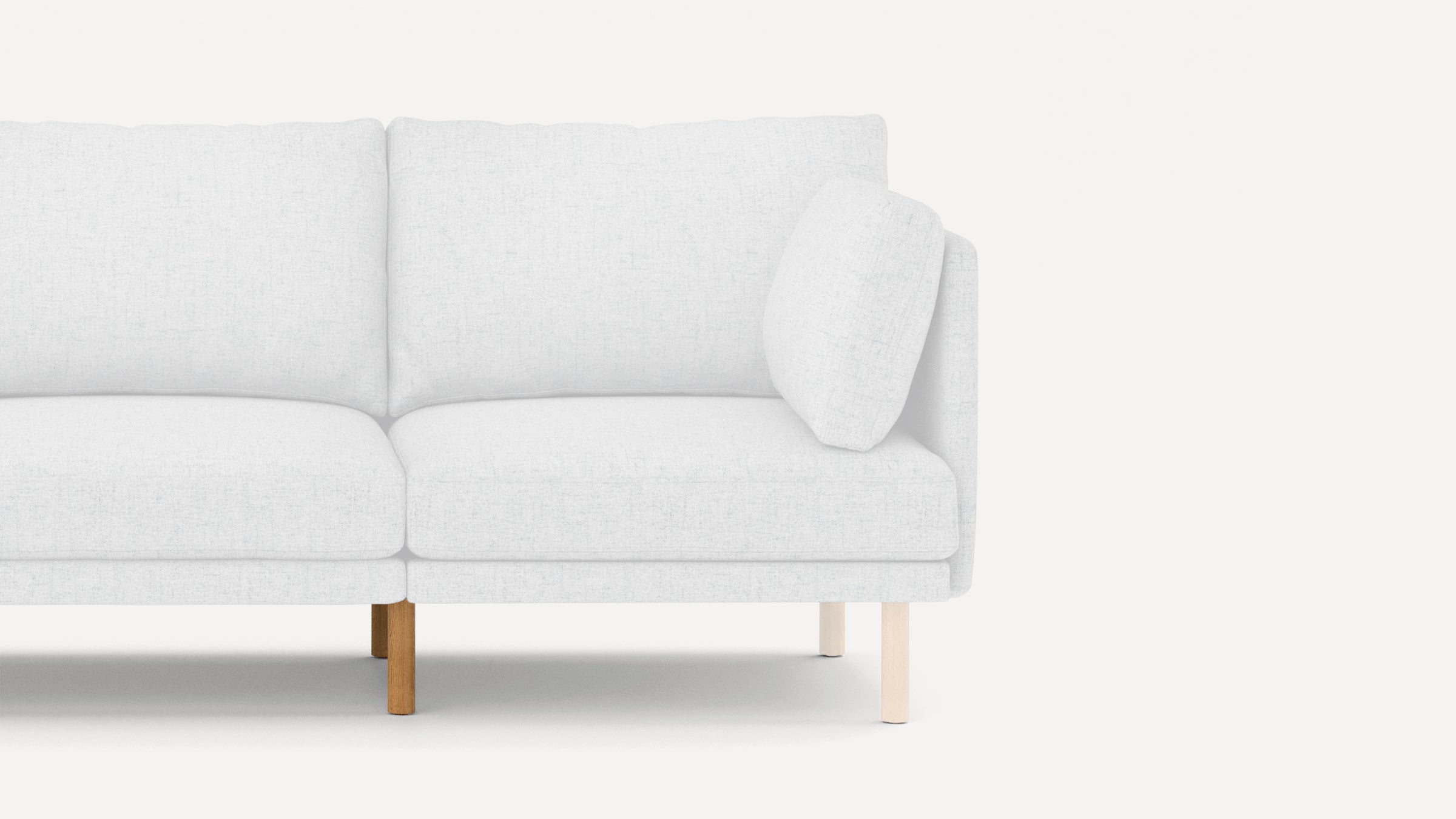 Partial view of a modern light gray fabric sofa with wooden legs and a matching side cushion on a plain white background.