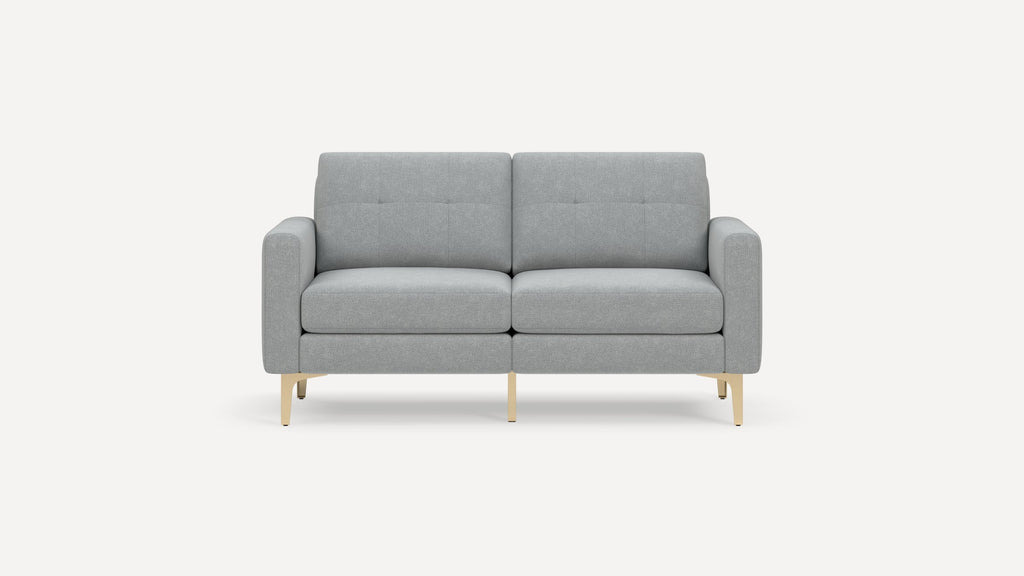 Modern light gray two-seater sofa with clean lines, tufted back cushions, padded armrests, and light wooden legs on a white background.