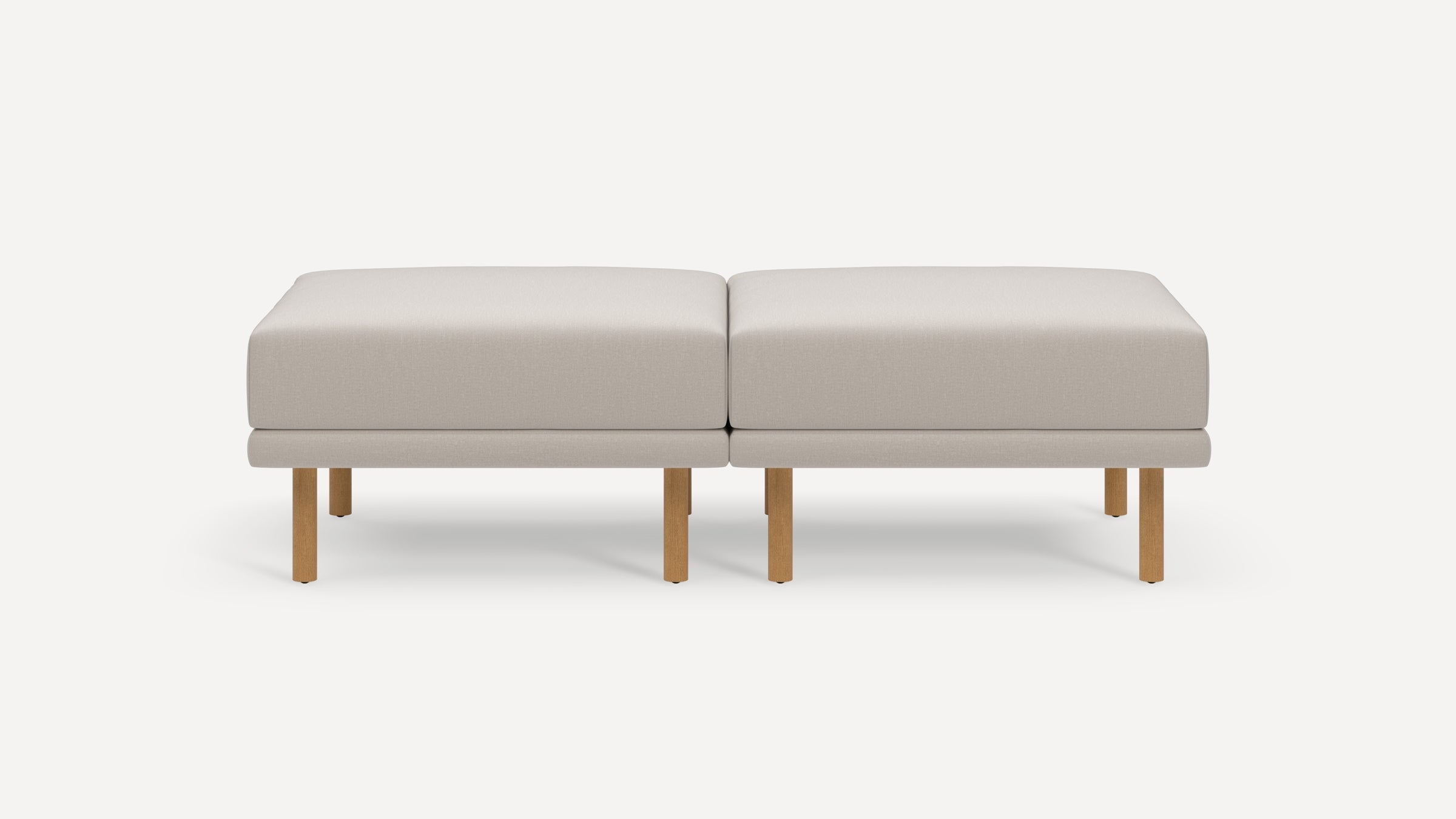 Two beige rectangular cushioned ottomans with wooden legs placed side by side on a plain white background.