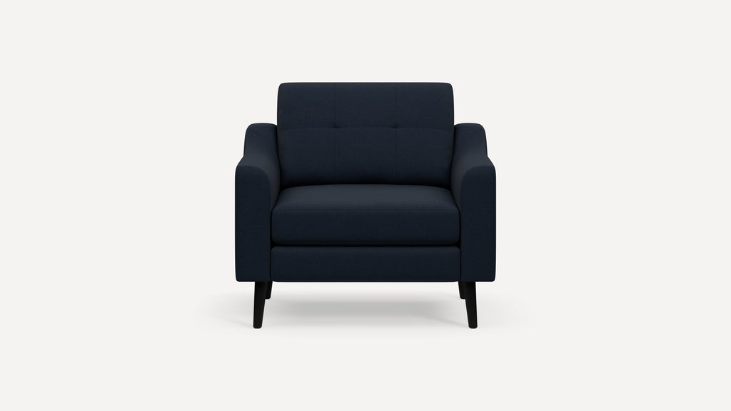 Front-facing navy blue upholstered armchair with tufted backrest, straight armrests, and black wooden legs on white background.