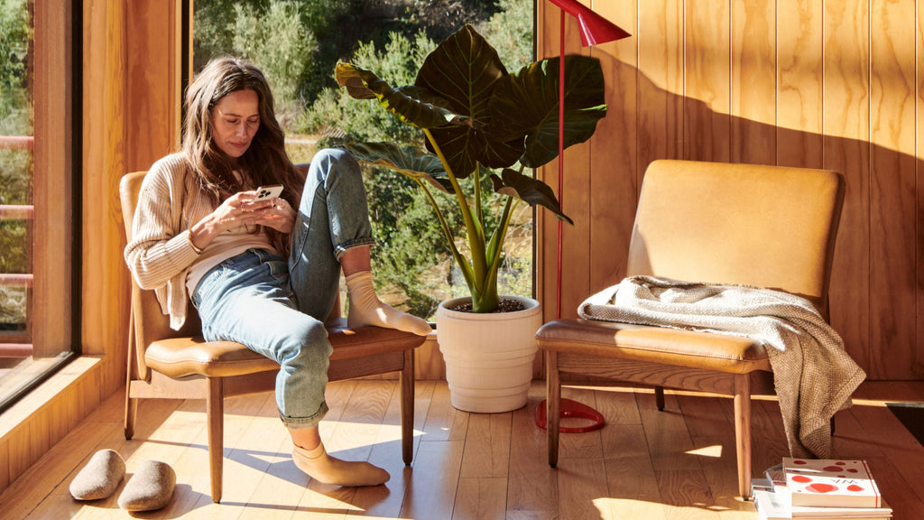 a woman sitting on a wooden chair using her phone