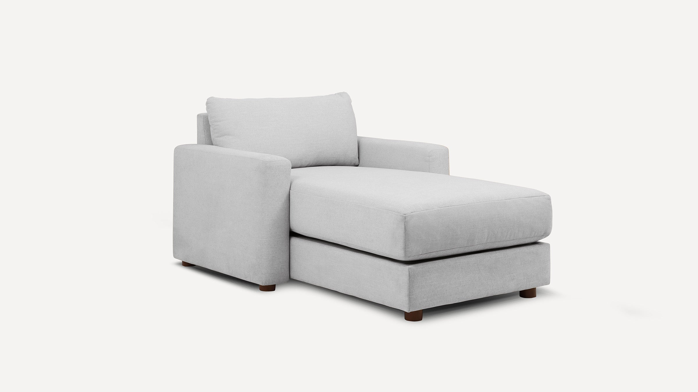Light gray upholstered chaise lounge with cushioned backrest and armrest, supported by short wooden legs.