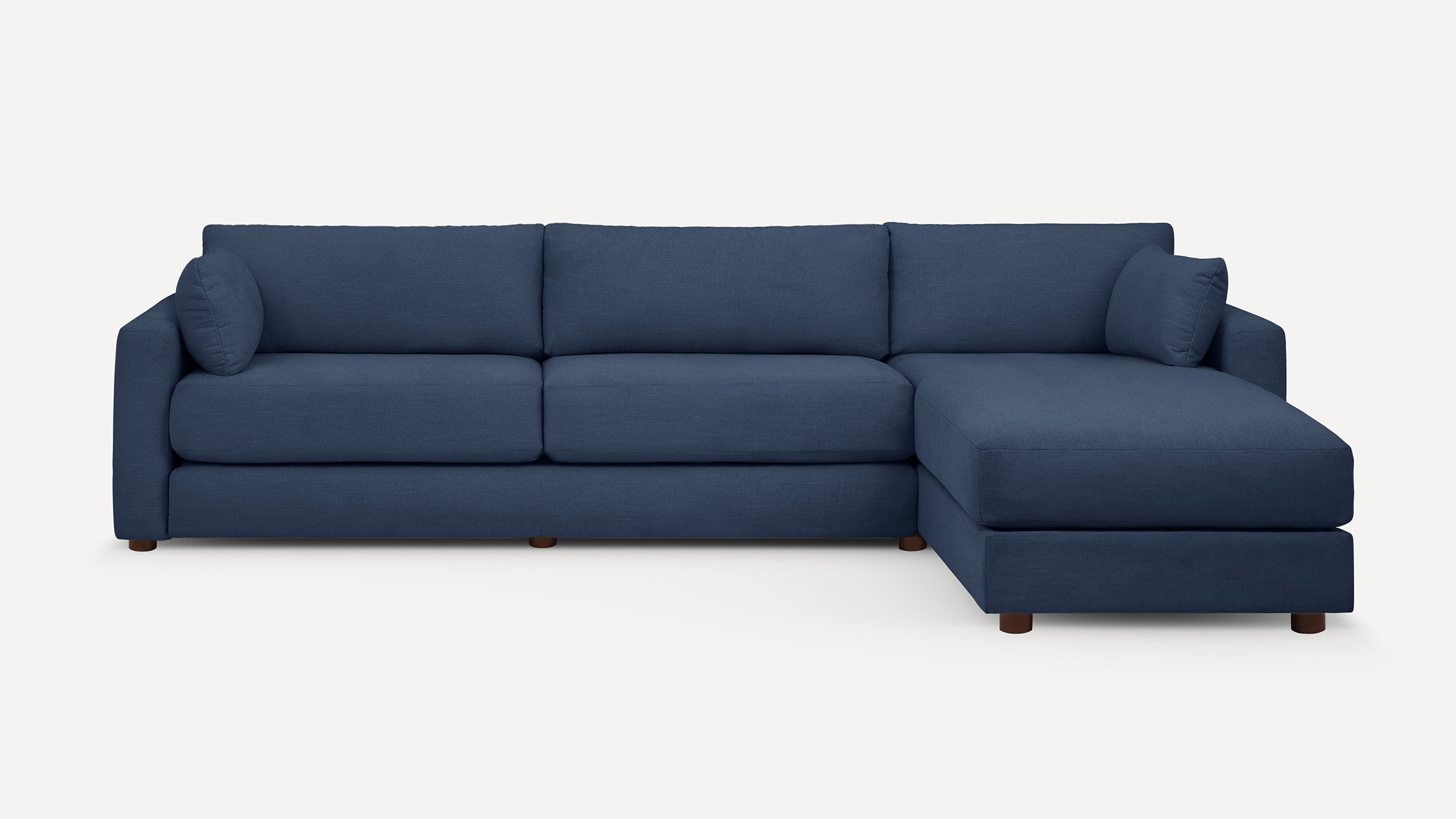 Modern navy blue sectional sofa with chaise lounge, featuring clean lines, plush cushions, and wooden legs on a plain white background.