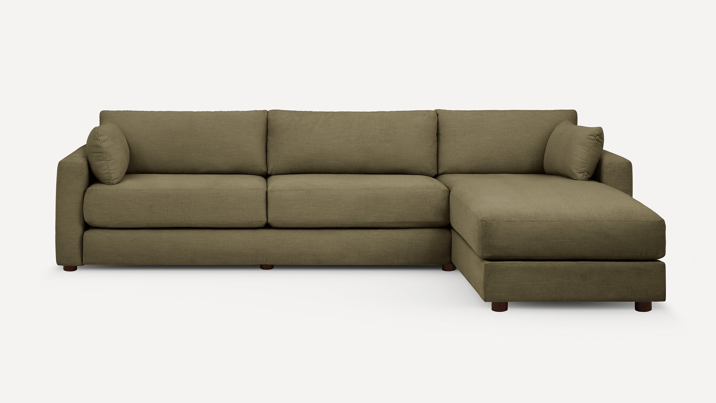 Modern L-shaped sectional sofa in olive green fabric with three cushions, two arm pillows, and wooden legs on white background.