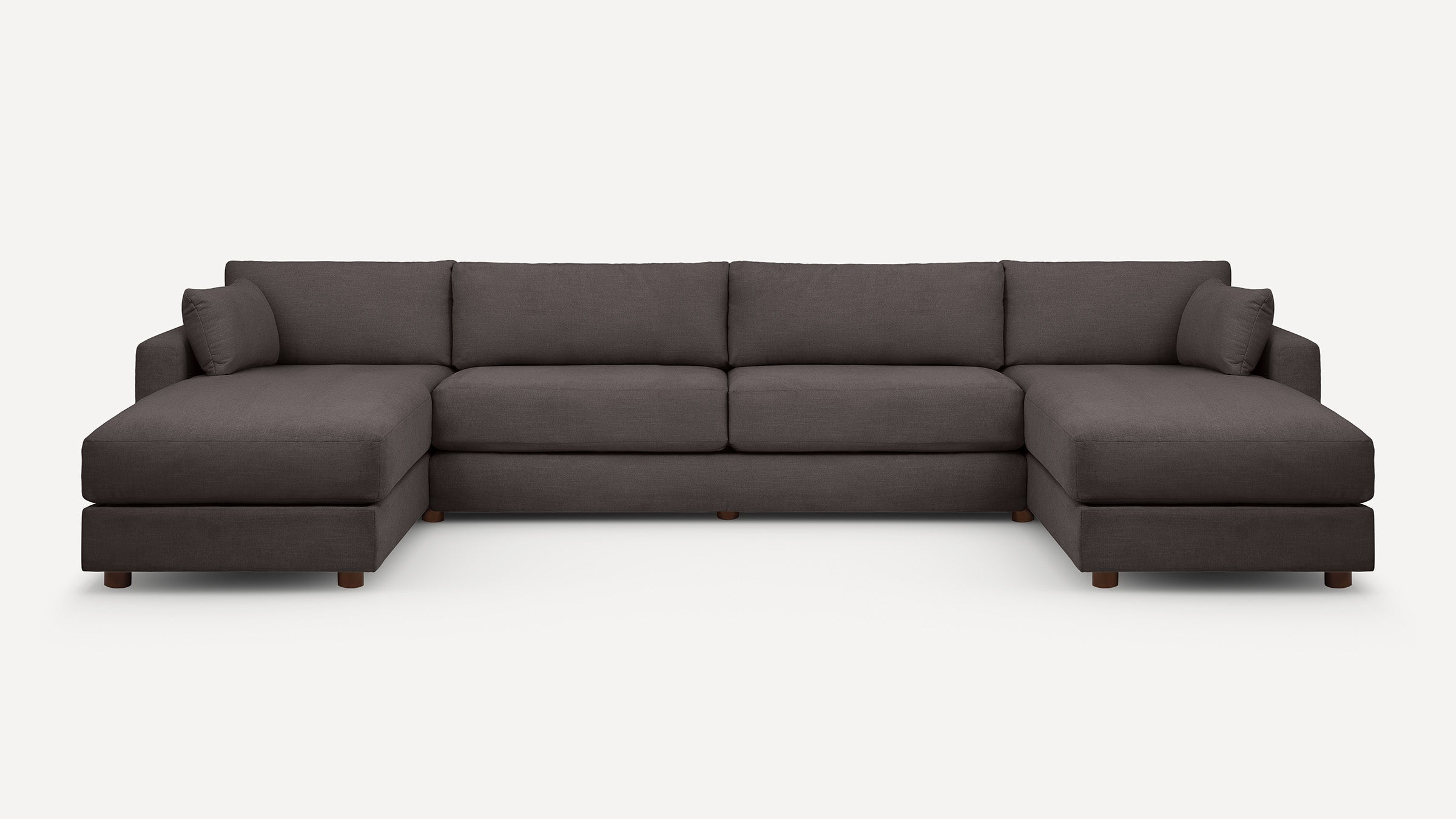 Large modern dark gray fabric sectional sofa with deep seats, two chaise lounges on each end, and six wooden legs.